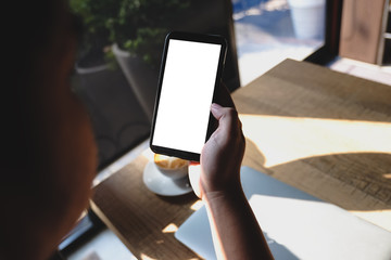 Close up of man using blank cell phone order products for shopping online within the cafe.