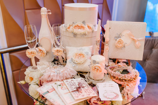 Wedding accessories, invitation, box, glasses, champagne, candles, brides garter lying on the table. Preparing for a wedding.