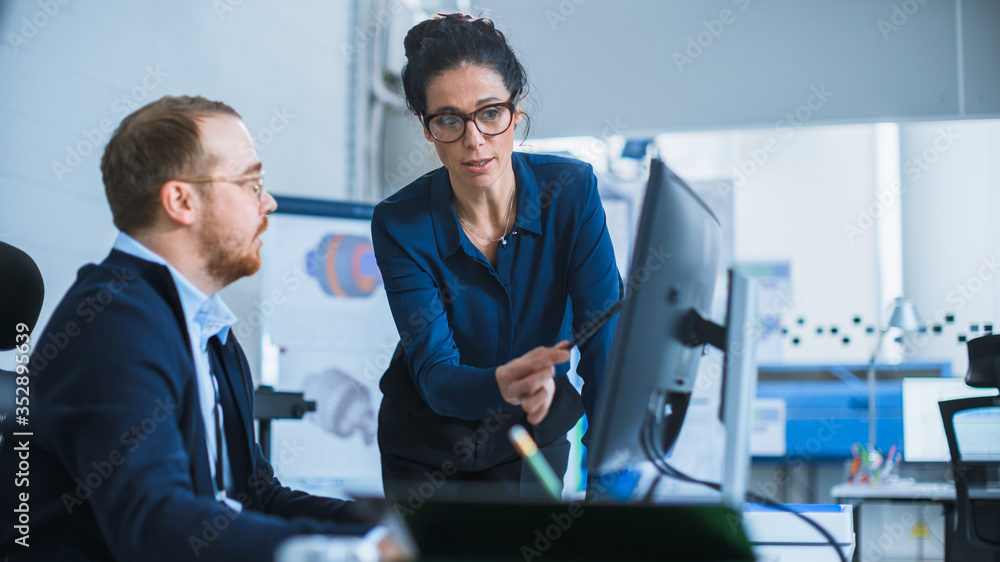 Leinwandbilder Modern Factory: Female Project Supervisor Talks to a Male Industrial Engineer who Works on Personal Computer. They use CAD Software for Design and Development of Hybrid Hydrogen Engine Prototype