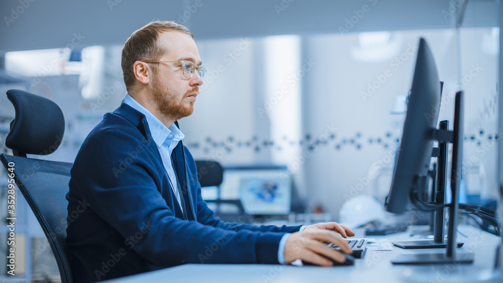 Poster Shot of a Heavy Industry Engineer Working on Personal Computer in Modern Industrial Factory with High-Tech CNC Machinery