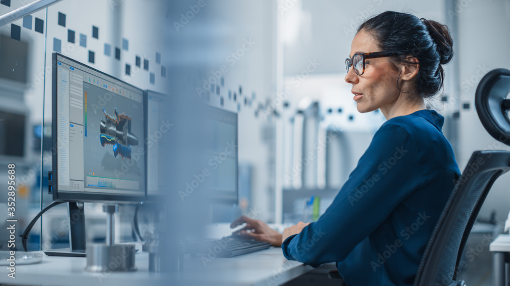 Aufkleber Industrial Female Engineer Working on a Personal Computer, Two Monitor Screens Show CAD Software with 3D Prototype of New Hybrid Hydrogen Engine and Charts. Modern Factory with High-Tech Machinery