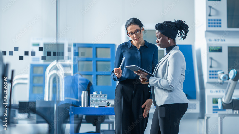 Poster Industrial Engineer Talks with Project Supervisor, They Use Digital Tablet Computer and Discuss Modern Factory Planning. Manufacturing Facility with CNC Machinery and Robot Arm Assembly Line