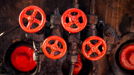 Closeup photo of red painted vavles and black pipes of vintage high pressure system on factory
