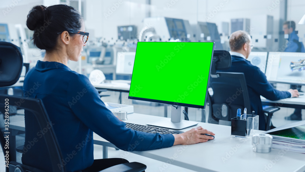 Aufkleber over the shoulder: female chief engineer working on personal computer, display is green mock-up scre