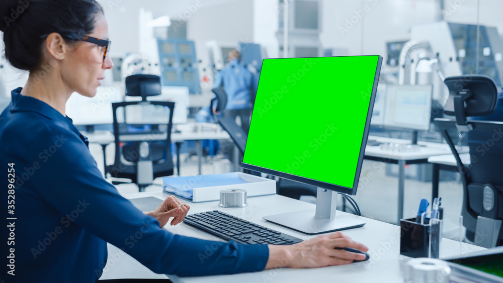 Aufkleber over the shoulder: female chief engineer working on personal computer, display is green mock-up scre