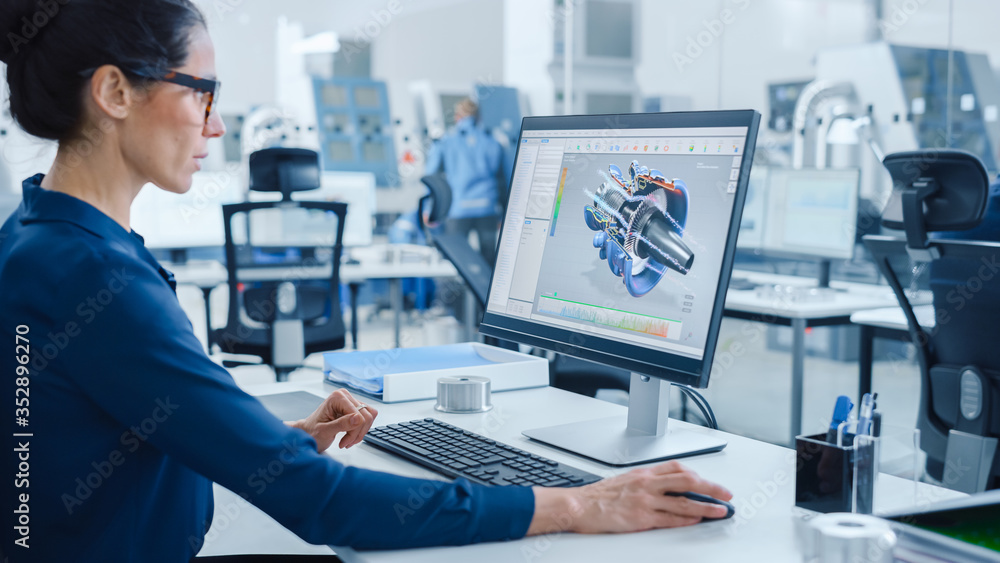 Fototapete Industrial female Engineer Working on a Personal Computer, Screen Shows CAD Software with 3D Prototype of Engine. Busy Factory with Professional Workers High-Tech Machinery