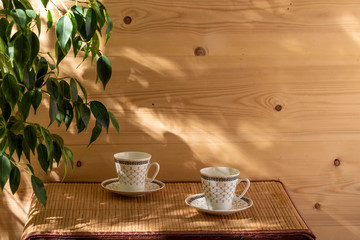 Two empty cups on the table in the patio lit by morning sun.