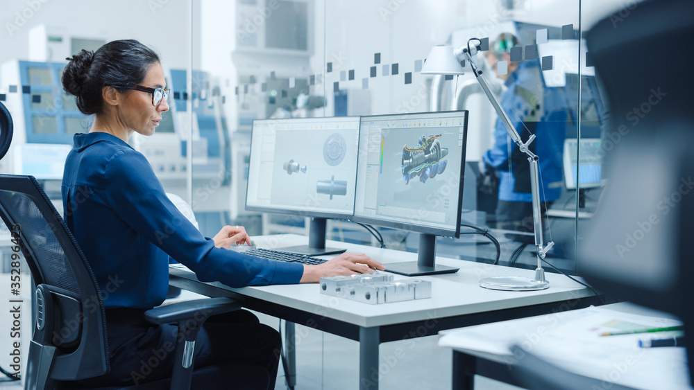 Poster Female Industrial Engineer Solving Problems, Working on a Personal Computer, Two Monitor Screens Show CAD Software with 3D Prototype of Engine Being Tested. Working Modern Factory