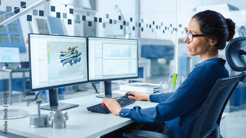 Poster Female Industrial Engineer Solving Problems, Working on a Personal Computer, Two Monitor Screens Show CAD Software with 3D Prototype of Zero-Emissions Engine Being Tested. Working Modern Factory