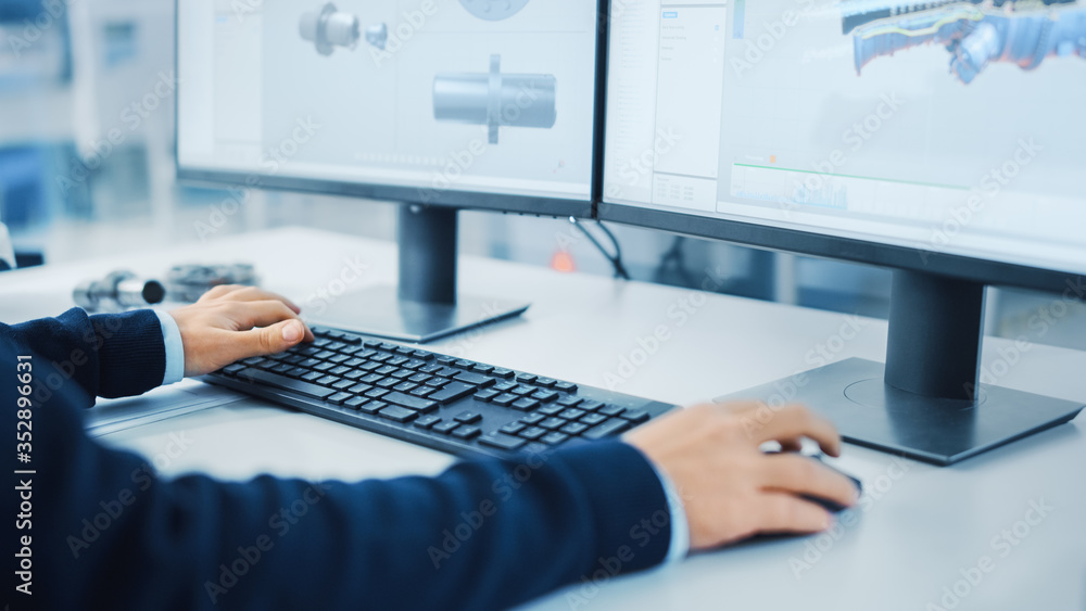 Poster Close-up Shot of Industrial Engineer Working on a Personal Computer, Using Mouse and Keyboard, Two Monitor Screens Show CAD Software with Machine Equipment in 3D.