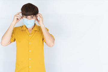 Asian handsome happy hipster man wearing a medical protection face mask for protect the...
