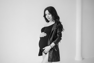 Fototapeta premium Pregnancy photo session in the style of Vogue. portrait of a young pregnant girl with long hair. Black and white