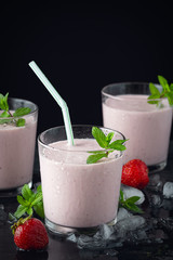 Glass of fresh strawberry shake, smoothie or milkshake and fresh strawberries on table. Healthy food and drink concept with juicy fruits