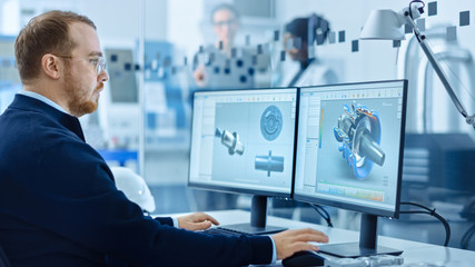 Heavy Industry Engineer Working on Personal Computer, Screen Shows CAD Software with 3D Prototype of Zero-Emissions Engine. Industrial Factory with High-Tech CNC Machinery.