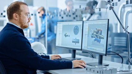 Heavy Industry Engineer Working on Personal Computer, Screen Shows CAD Software with 3D Prototype of Zero-Emissions Engine. Industrial Factory with High-Tech CNC Machinery.