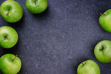 Fresh green granny smith apples framing grey background, top view, banner. Vegan or diet food concept. Background layout with free text space