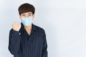Fototapeta na wymiar Asian handsome happy hipster man wearing a medical protection face mask for protect the coronavirus, filter dust PM 2.5 and cold and raise her hand to fight them on white background