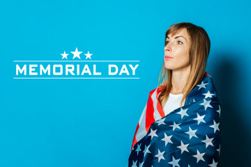 Young woman wrapped in usa flag on a blue background. USA Visa Concept, English, Independence Day, July 4th, Memorial Day. Travel to the USA