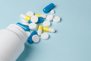 Assorted pharmaceutical medicine pills, tablets and capsules over blue background