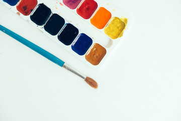 Set of watercolor paints and brush for painting on a white background. Top view. Copy, empty space...
