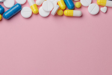 Obraz premium Assorted pharmaceutical medicine pills, tablets and capsules over a pink background