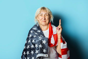 Old woman holds American flag on a blue background. Independence Day celebration concept, memorial day, emigration, US flag