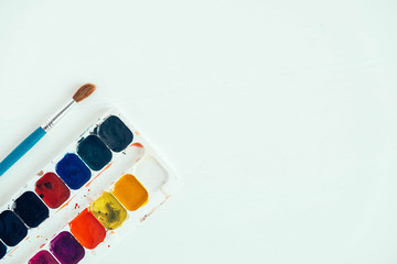 Set of watercolor paints and brush for painting on a white background. Top view. Copy, empty space for text