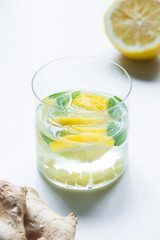 selective focus of fresh lemonade in glass near lemon and ginger root on white background