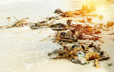 Selective focus picture of garbage and waste on the beach with orange light background