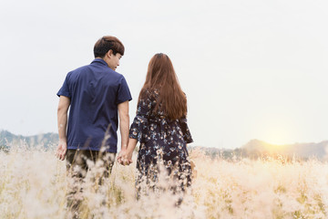 Summer portrait of couple standing together in meadow on sunny day. Couple having fun on their summer holiday.