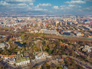 Obraz premium Beautiful top view of the zoo in Budapest. Top view of the railway, houses and city park. Spring. Mountains and beautiful clouds in the background.