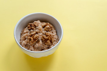 Spelled porridge with walnut. Proper nutrition concept. Yellow background. Farro for breakfast.