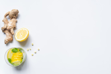 top view of fresh lemonade in glass near lemon and ginger root on white background