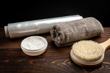 Fototapeta na wymiar Wooden massage brush, cream and towel on dark wooden background.