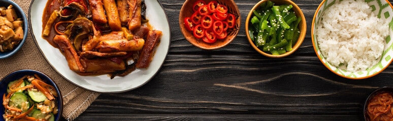horizontal image of korean traditional and spicy dishes near chopsticks and cotton napkin on wooden surface