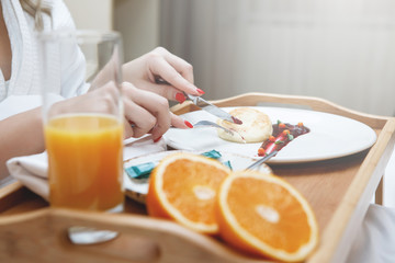Female hands and breakfast on a tray.