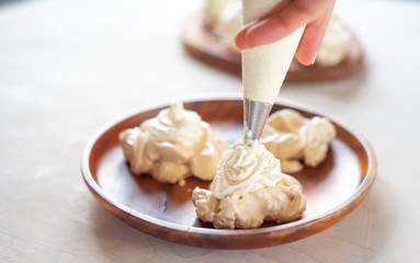 the process of creating Pavlova dessert, decorating the meringue with cream from the culinary bag