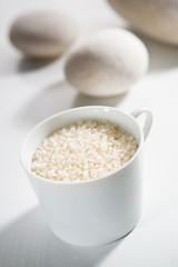 Round grain rice in the white cup and eggs ready for cooking