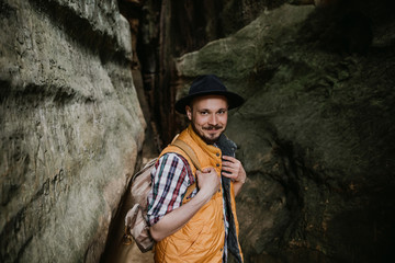 portrait of a young bearded man in hat standing on rock