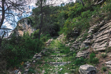 A picturesque view of a hiking path with stone stairway in the French Alps mountains on a sunny day (Touet-sur-Var, Alpes-Maritimes, Provence, France)