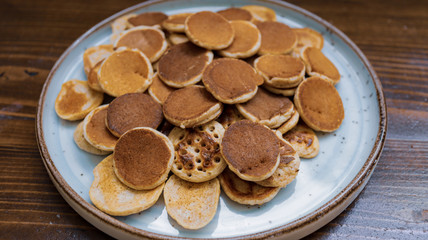 Freshly baked a plate of poffertjes, traditional Dutch Mini Pancakes without any other ingredients with the wooden background