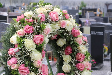 Blumenschmuck in Form eines Blütenkranzes mit Rosen nach einer Beisetzung auf einem Friedhof