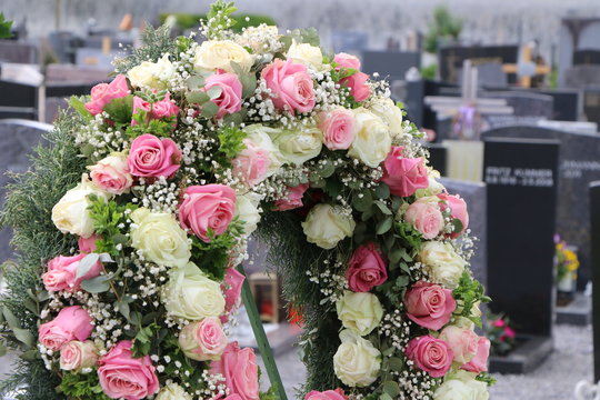 Blumenschmuck in Form eines Bl&uuml;tenkranzes mit Rosen nach einer Beisetzung auf einem Friedhof