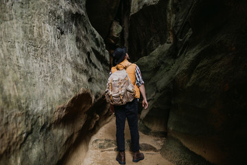 Fototapeta na wymiar Young man hiking at mountain rock with backpack, orange jacket. Travel concept