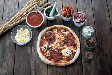 An amazing meat styled pizza with all the ingredients around.