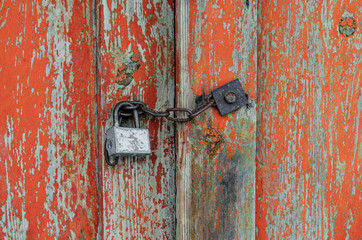 Old wooden door closed by a primitive padlock on a chain