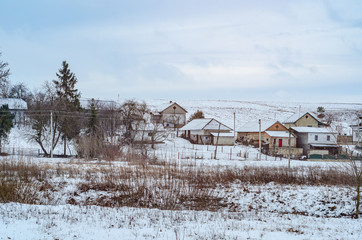 Scenic winter view of traditional Ukrainian village, with snow-covered houses and countryside landscape