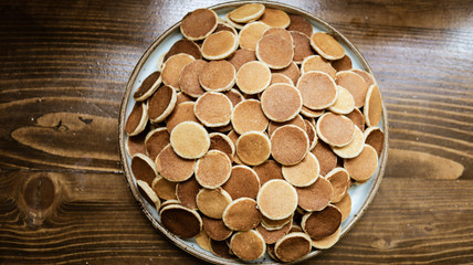 Freshly baked a plate of poffertjes, traditional Dutch Mini Pancakes without any other ingredients with the wooden background