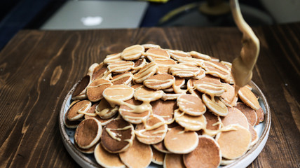 A plate of Dutch Mini Pancakes, poffertjes with peanut butter on the wooden background