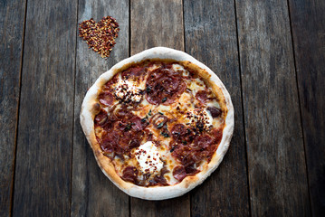 Variations on a heart shaped dried chilli and a pizza is laying on the nice old wooden table